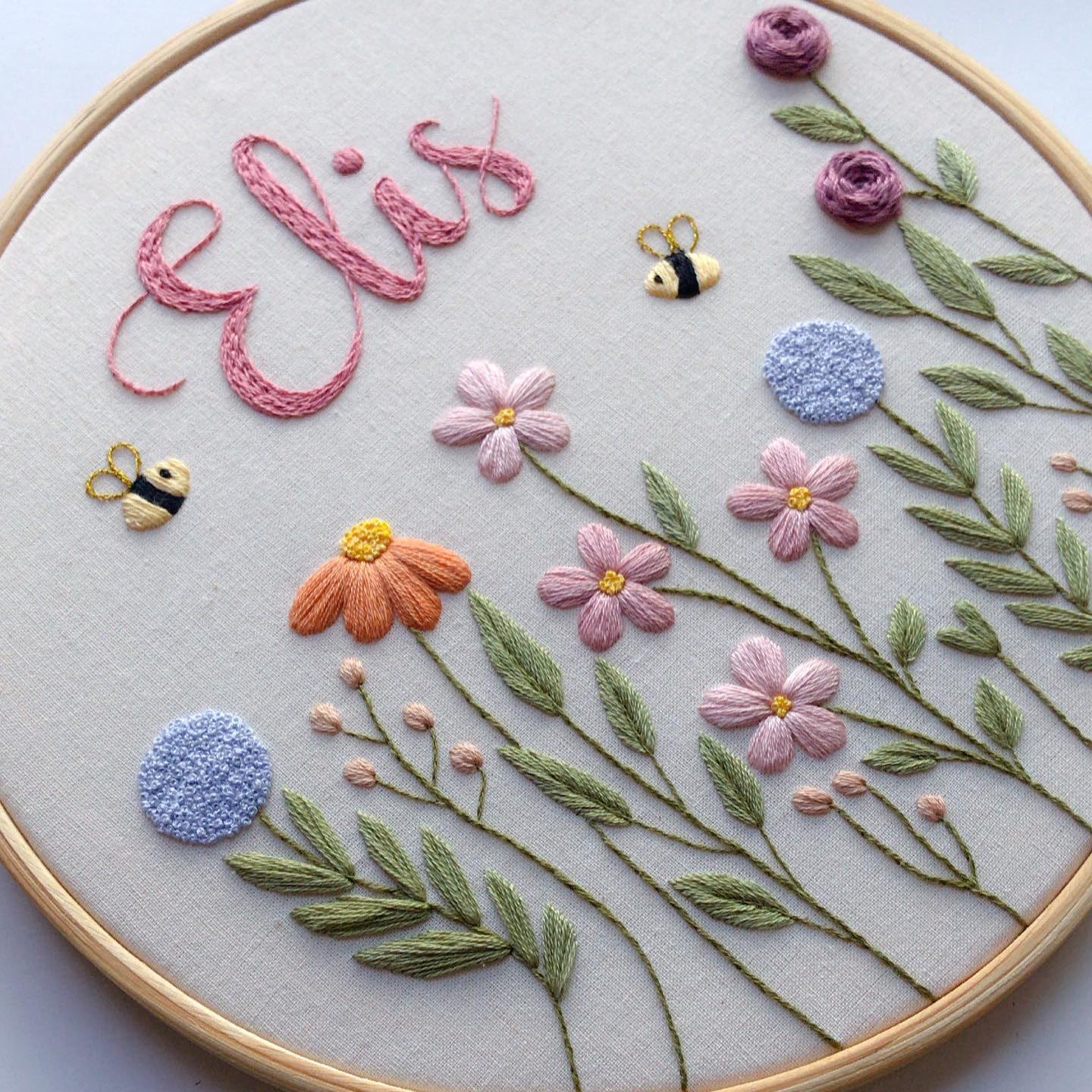 Bastidor bordado com o nome Elis, flores, abelhas e folhagens