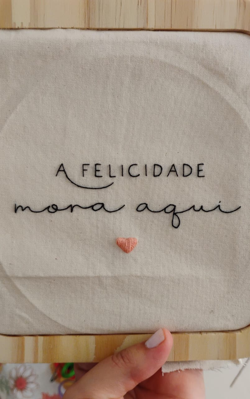 “A felicidade mora aqui” — lettering bordado com coração em relevo